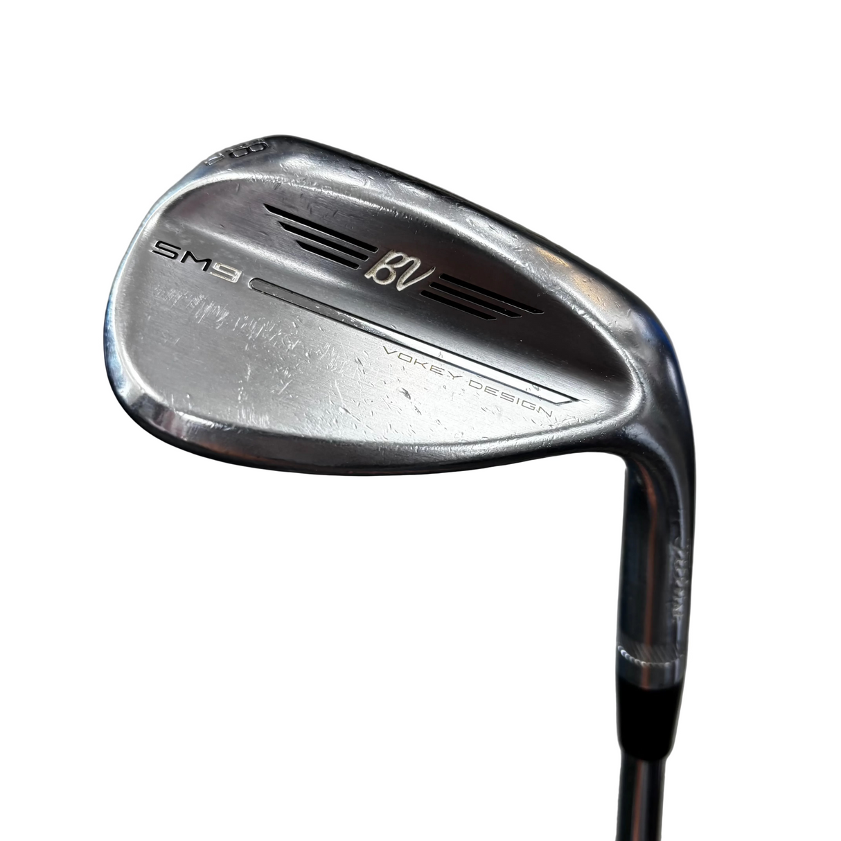 A close-up shot of a Wilson golf iron club head, specifically a SM3 BVC model, resting on a dark blue mat on a gray concrete floor.