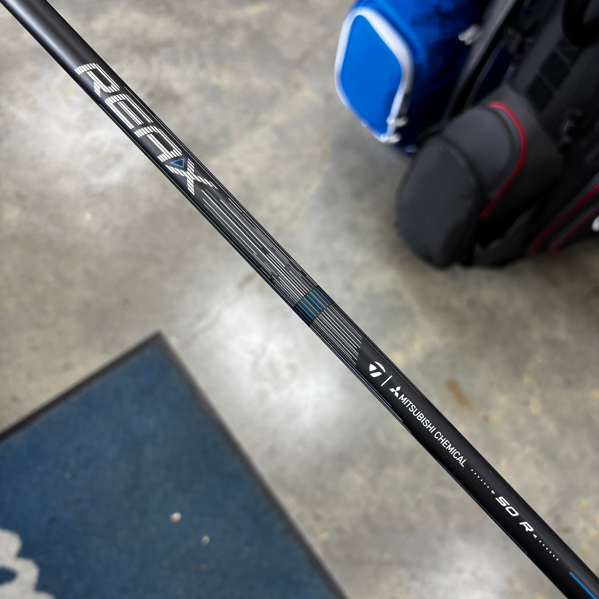 Golf club shaft with 'REAX' branding on a concrete floor.