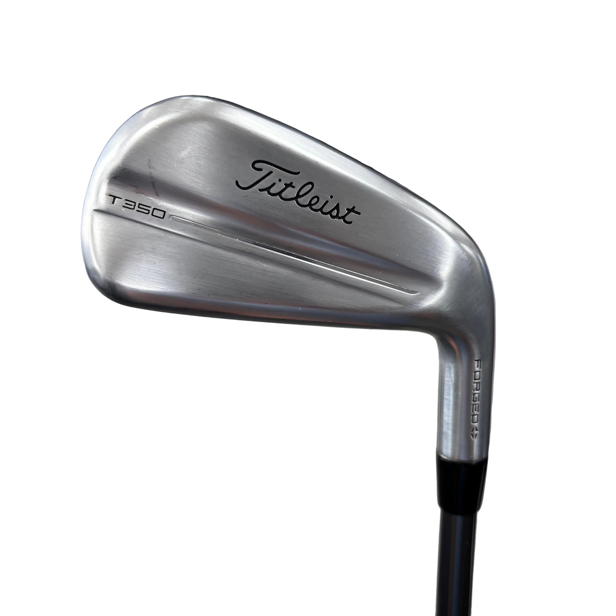 A silver Titleist T-350 iron golf club head shown close-up, with the Titleist logo engraved on the back. The club is photographed in what appears to be a store or garage setting with a concrete floor and blurred background.