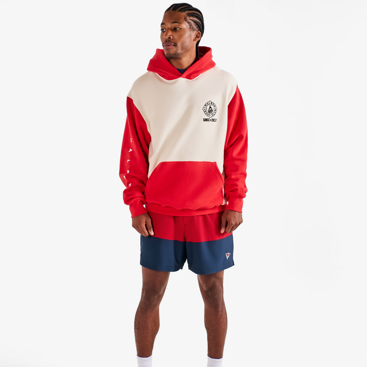 Person wearing a red and beige hoodie with blue shorts on a white background