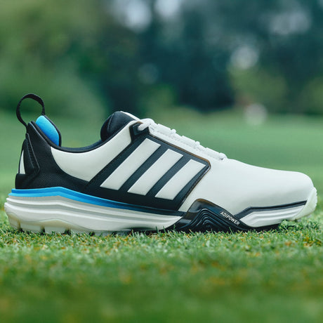 White and black Adidas golf shoe with blue accents on grass