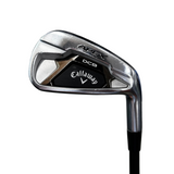 A Callaway Apex DCB iron golf club head shown in a close-up shot, standing upright on a black shaft. The Callaway and Apex DCB branding are clearly visible on the clubface.