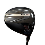 A close-up shot of a black and dark gray Callaway GT2 9-iron golf club head, showing the GT2 and 9.0 branding, set against a blurred indoor background.