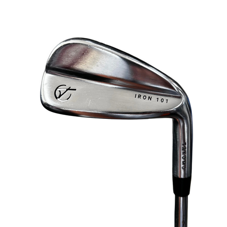 A close-up shot of a Callaway iron golf club head with 'GT' and 'IRON 101' engraved on the polished metal surface, resting on a gray concrete floor.