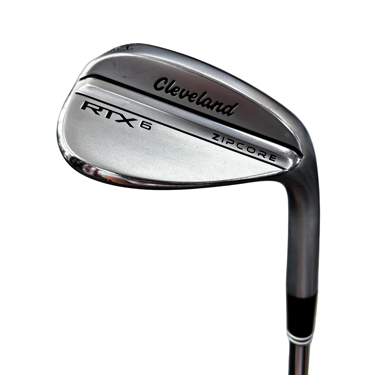A close-up shot of a Cleveland RTX 6 ZIPCORE golf wedge, showing the polished metal club head and part of the shaft against a blurred concrete background.