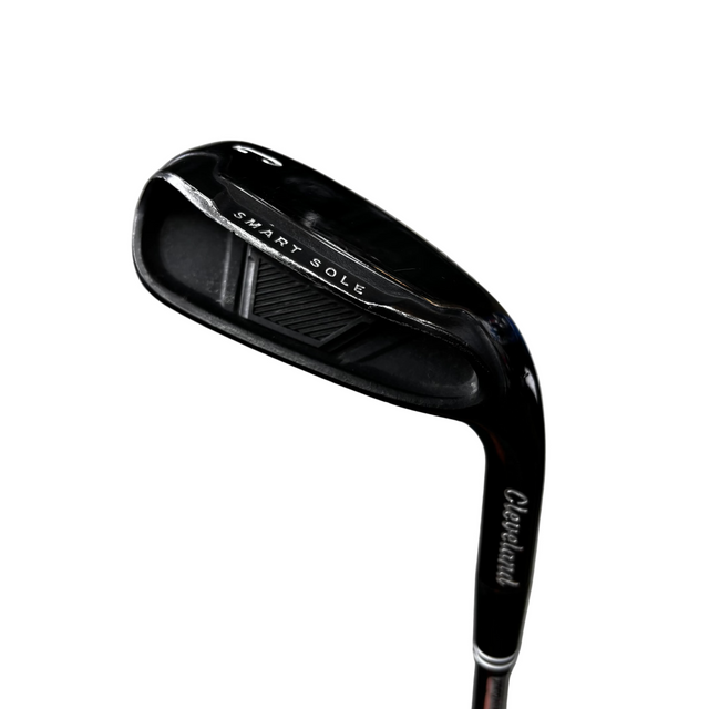 A close-up of a Cleveland Smart Sole golf iron club head, showing the brand name and model text on the black metal clubface, photographed against a gray concrete floor.