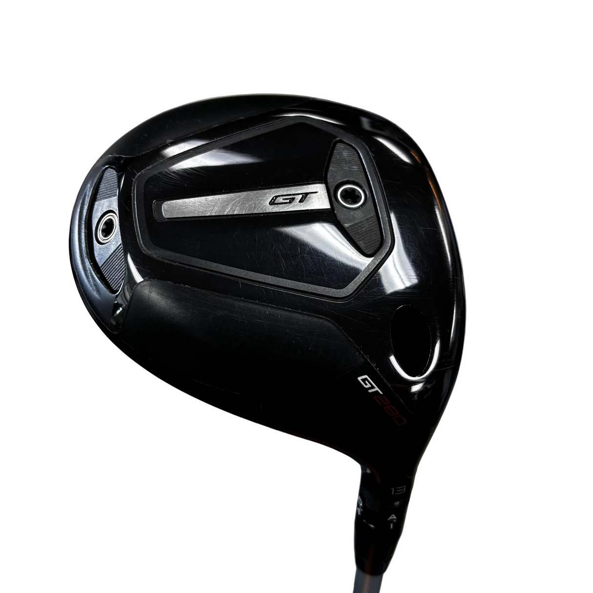 A black titleist golf driver with a metallic silver GT logo on the back, photographed on a gray concrete floor.