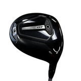 A black titleist golf driver with a metallic silver GT logo on the back, photographed on a gray concrete floor.