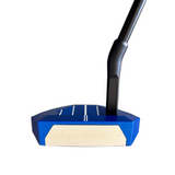 Blue and beige golf putter head on a gray surface with a blurred green mat in the background.