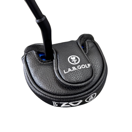 Close-up of a golf putter with L.A.B. Golf branding on a concrete floor.