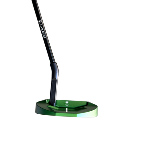 Close-up of a green golf putter head on a gray surface with a blurred background