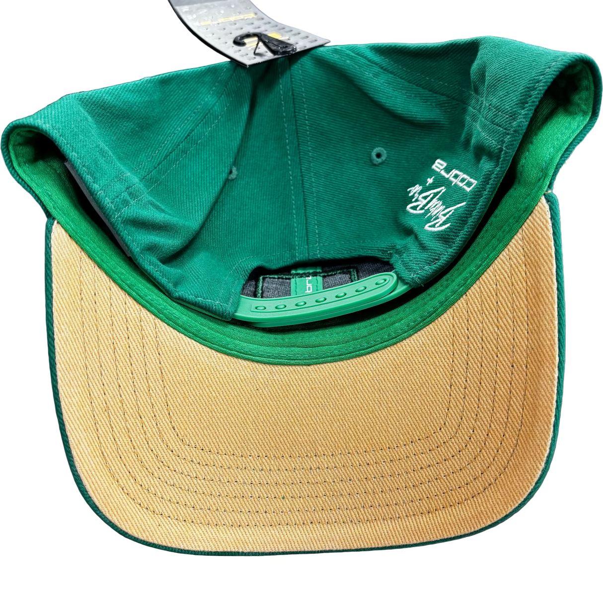 Green and beige cap with brand logo on a dark surface