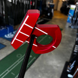 Close-up of a red and black putter head on a golf simulator with blurred background