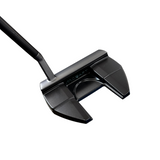 Close-up of a black golf putter on a concrete floor with blurred background