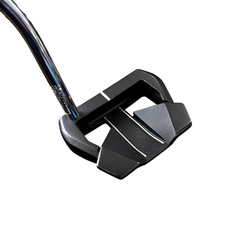 Close-up of a golf putter on a concrete floor with a blurred background