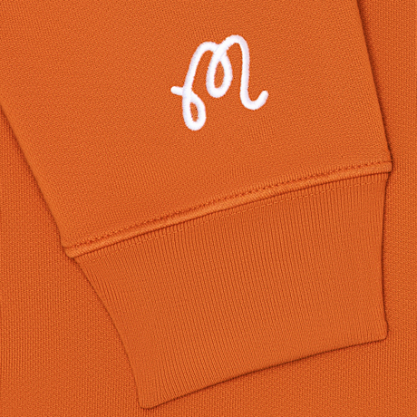 Close-up of an orange hoodie with a white logo on the chest pocket.