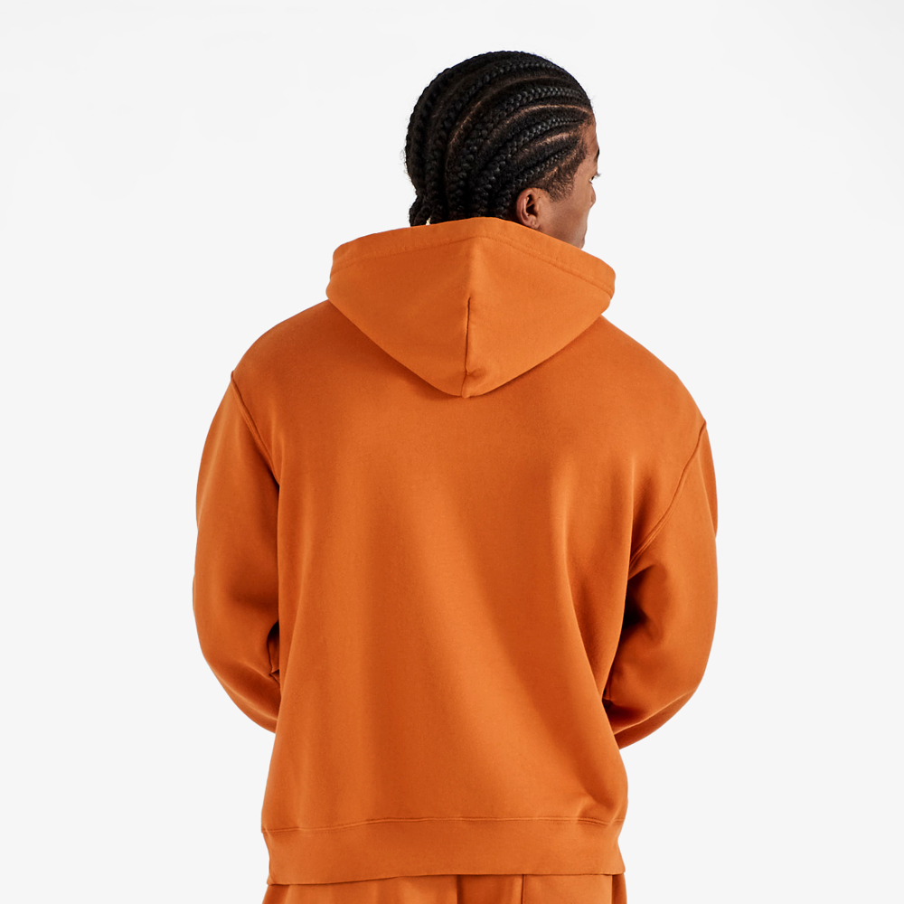 Person wearing an orange hoodie and pants on a white background