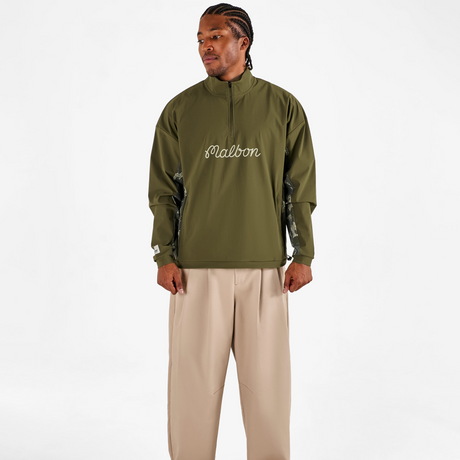 Person wearing a green jacket with 'Fusalba' branding and beige pants on a white background