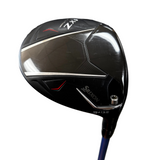 A close-up of a Srixon ZXi 13.5° golf club head, showing the black carbon-fiber textured face with silver and red accents, set against a blurred indoor background.